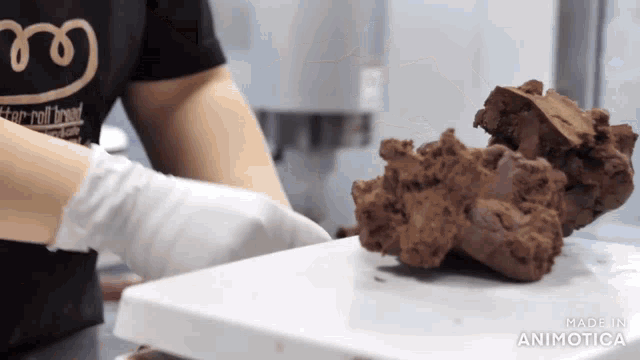 a person wearing a black shirt that says better roll bread is holding a piece of chocolate