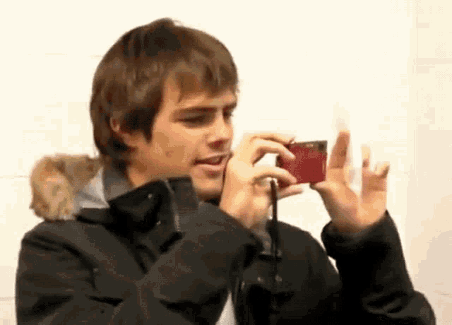 a young man is taking a picture with a red camera