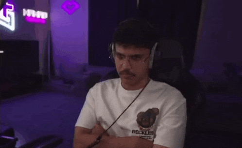 a man wearing headphones is sitting in a chair with his arms crossed and looking at the camera .