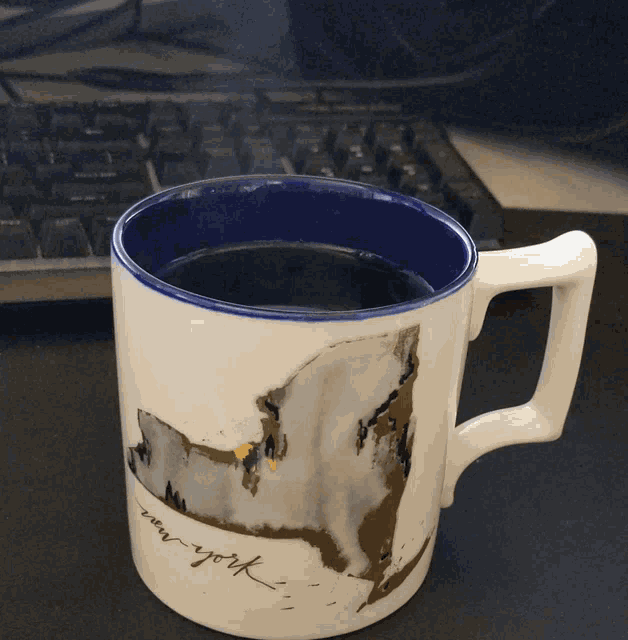 a new york mug sits on a desk next to a keyboard