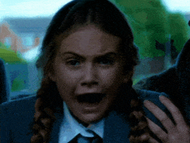 a girl in a school uniform is making a funny face