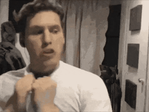 a man in a white shirt is adjusting his tie