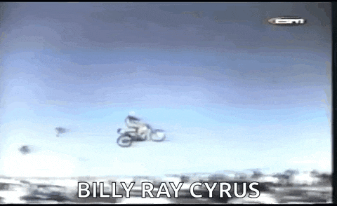 a man is riding a motorcycle in the air with the words `` billy ray cyrus '' behind him .