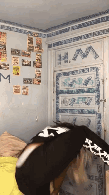 a person laying on a bed in front of a door with the letter m written on it