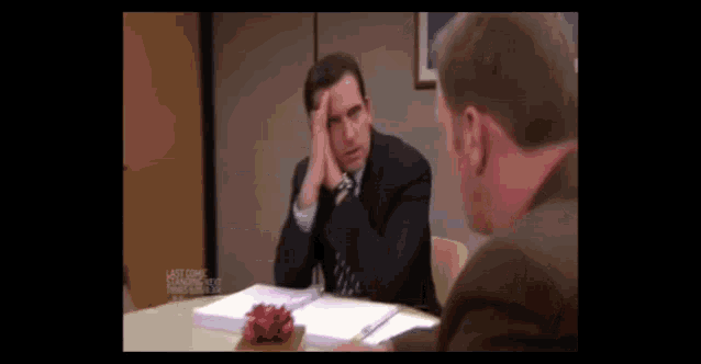 a man in a suit and tie is sitting at a table with another man .