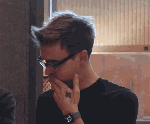 a man wearing glasses and a watch has a tattoo on his finger that says 88