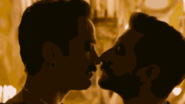 a man with a mustache kissing another man on the nose