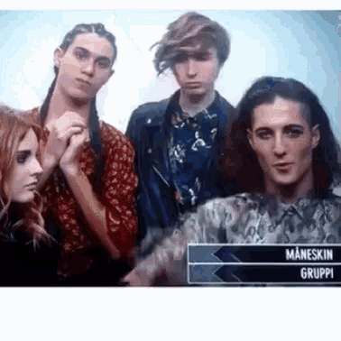 a group of people standing next to each other in front of a sign that says maneskin gruppo .