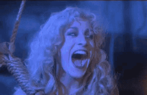 a woman with long blonde hair is screaming with her mouth open in a blue light .