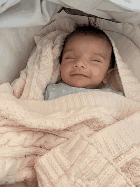 a baby is wrapped in a pink blanket and smiling for the camera