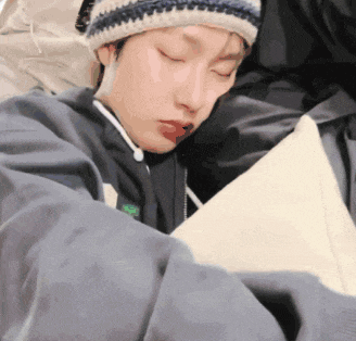 a person wearing a hat is sleeping on a bed with their eyes closed