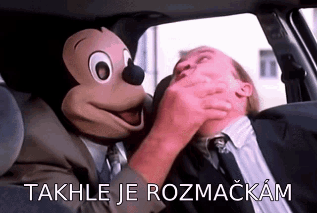 a man in a suit and tie is being held by a mickey mouse mask