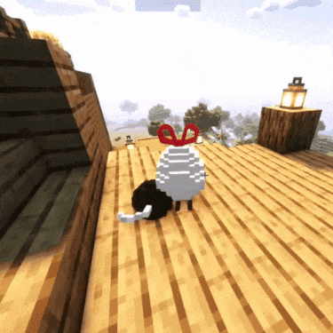a black and white sheep with a red bow on its head is standing on a wooden deck