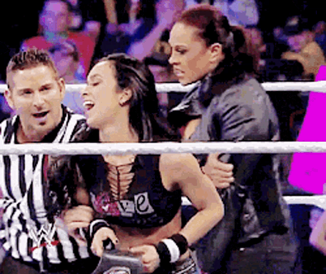 a woman in a wrestling ring with a referee behind her