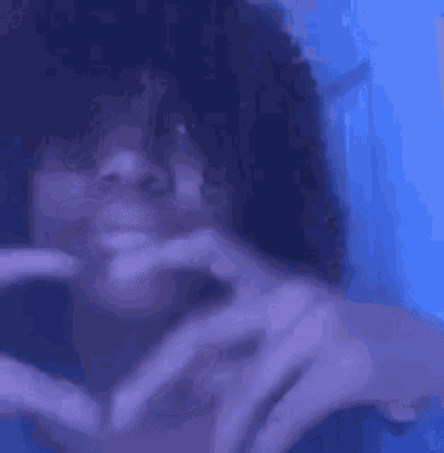 a woman is making a heart shape with her hands .