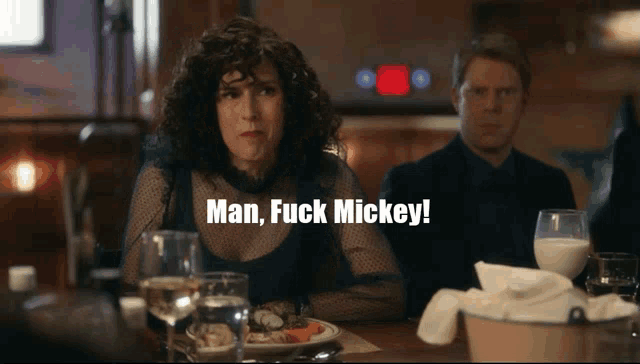 a woman sits at a table with a plate of food and a glass of milk and says man fuck mickey