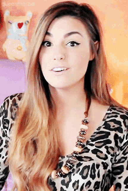 a woman wearing a leopard print top and a necklace with the name queenmarzia written on the bottom