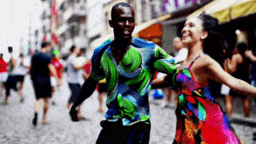 a man in a green shirt is dancing with a woman in a red dress