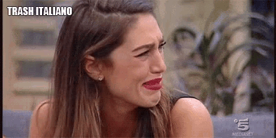 a woman is crying while sitting on a couch with the words trash italiano written on the bottom .