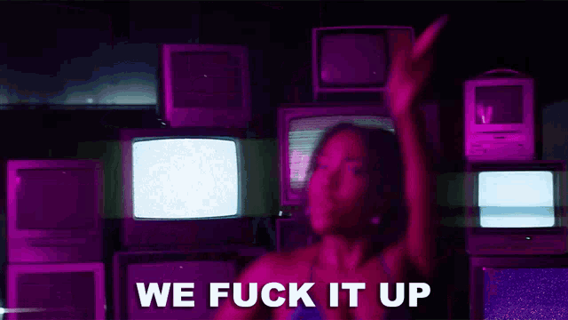 a woman is dancing in front of a wall of televisions and the words we fuck it up are written on the screen