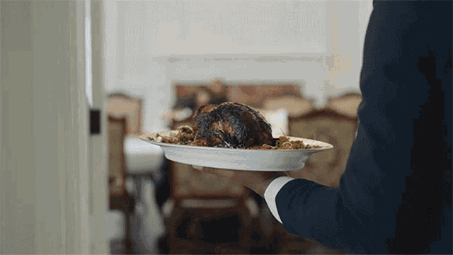 a man in a suit is holding a plate of food in his hand