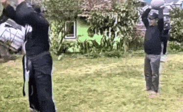 two men are standing in a grassy field with their arms in the air