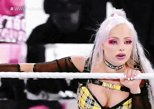 a woman in a plaid top is leaning on a rope in a wrestling ring with the hashtag #wwesayhaul