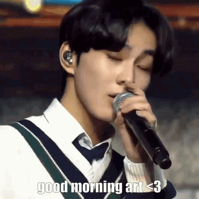 a young man singing into a microphone with the words " good morning art < 3 " above him