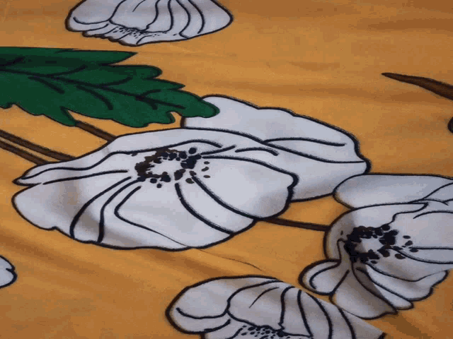 a yellow cloth with white flowers and green leaves on it
