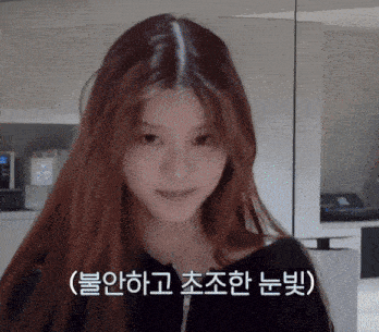 a woman with long red hair is looking at the camera with a foreign language behind her