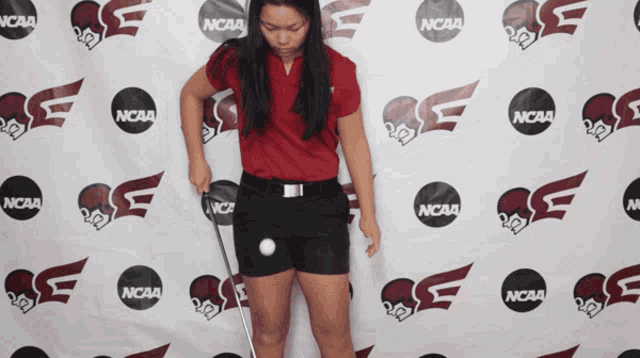 a woman stands in front of a ncaa banner