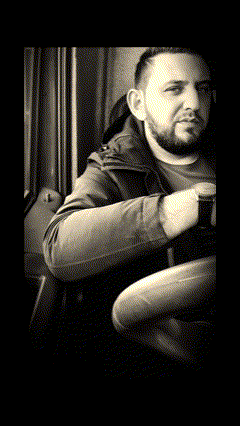 a man with a beard sits in a dark room