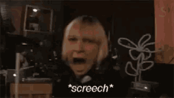 a woman with blonde hair is screaming with her mouth open in a dark room .