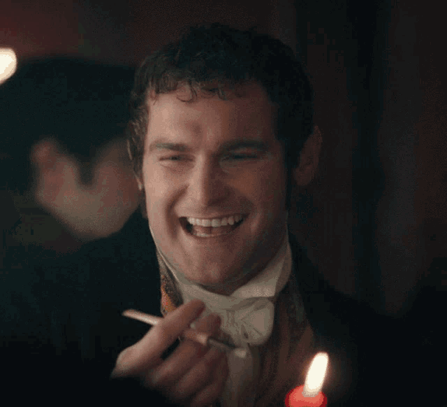 a man in a tuxedo is smiling and holding a cigarette