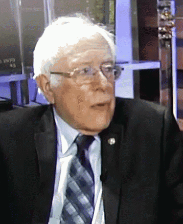a man wearing glasses and a suit is talking on a microphone