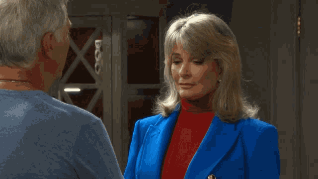 a woman in a blue jacket is talking to a man