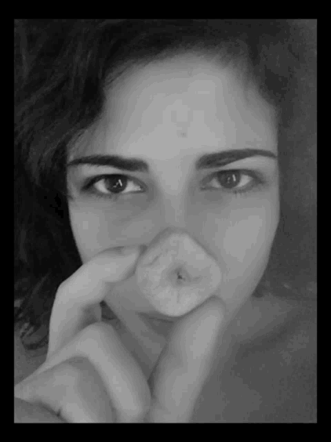 a black and white photo of a woman covering her nose with her finger