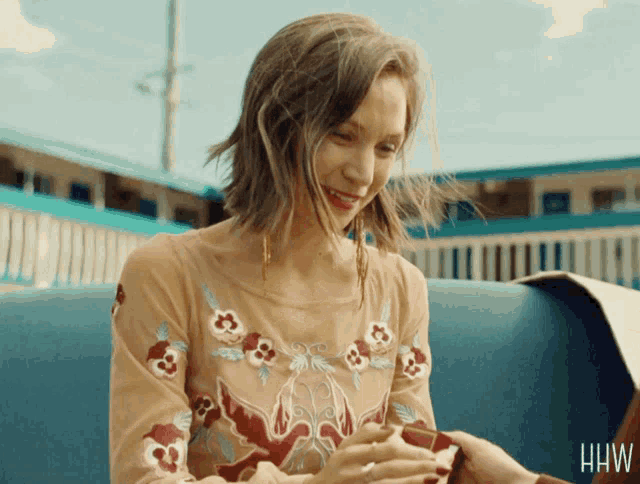a woman in a floral dress is smiling and holding someone 's hand with the letters hhw on the bottom right