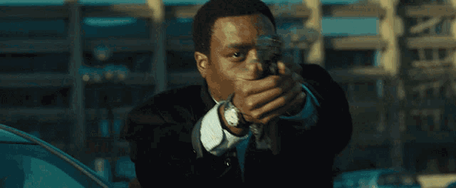 a man in a suit and tie is pointing a gun at the camera