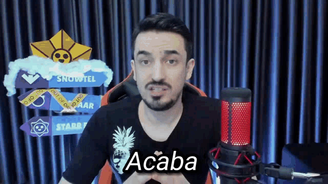 a man sitting in front of a microphone with the word acaba on his chest