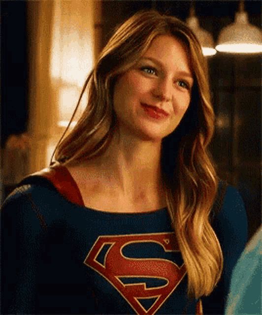 a woman in a superman costume is smiling while standing in a room .