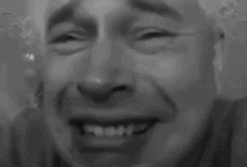 a close up of a man 's face in a black and white photo with his mouth open .