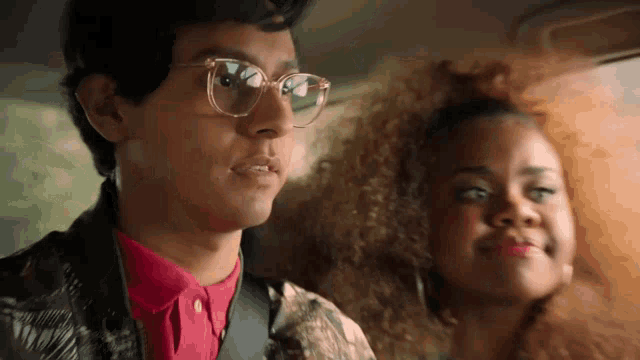 a man wearing glasses is sitting next to a woman with curly hair