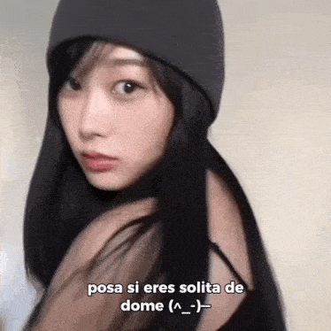 a woman wearing a beanie and a black tank top says posa si eres solita de dome ( _ )