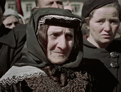 a woman wearing a scarf and a hat looks at the camera