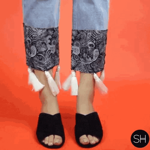a woman wearing a pair of black sandals with tassels on the ankle