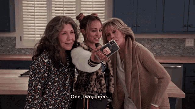 three women are posing for a picture and one of them says " one two three "