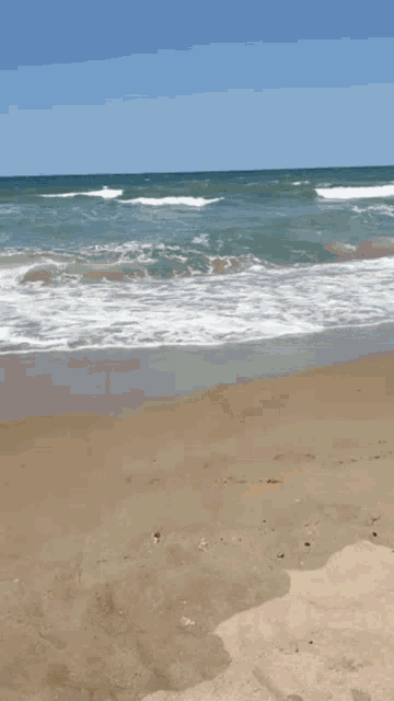 a little boy in yellow shorts is walking on a sandy beach