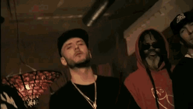 a man wearing a dream crew shirt stands with two other men