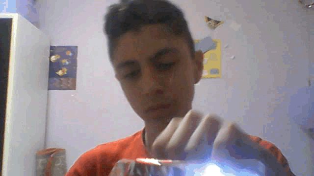a young boy in an orange shirt is holding a lighter in his hand